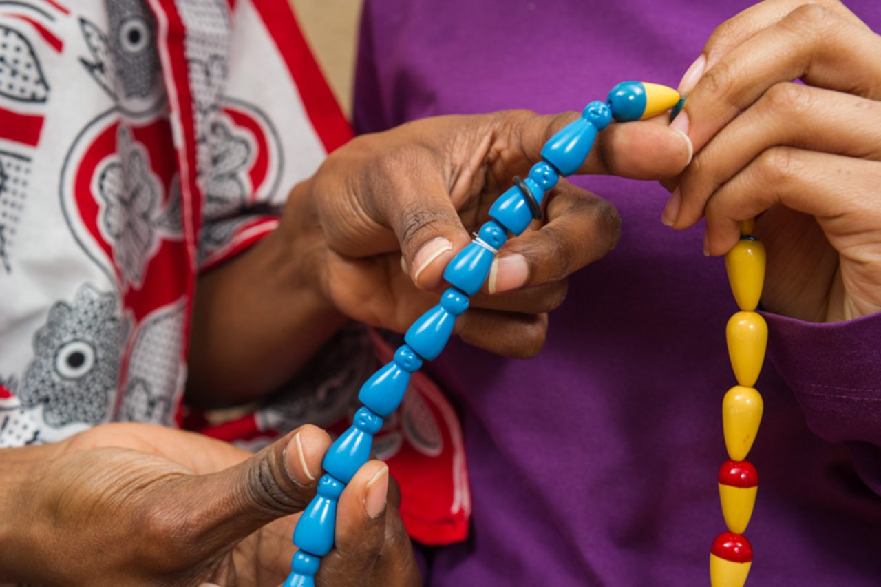 Eine Frau hält eine bunte Kette in der Hand.