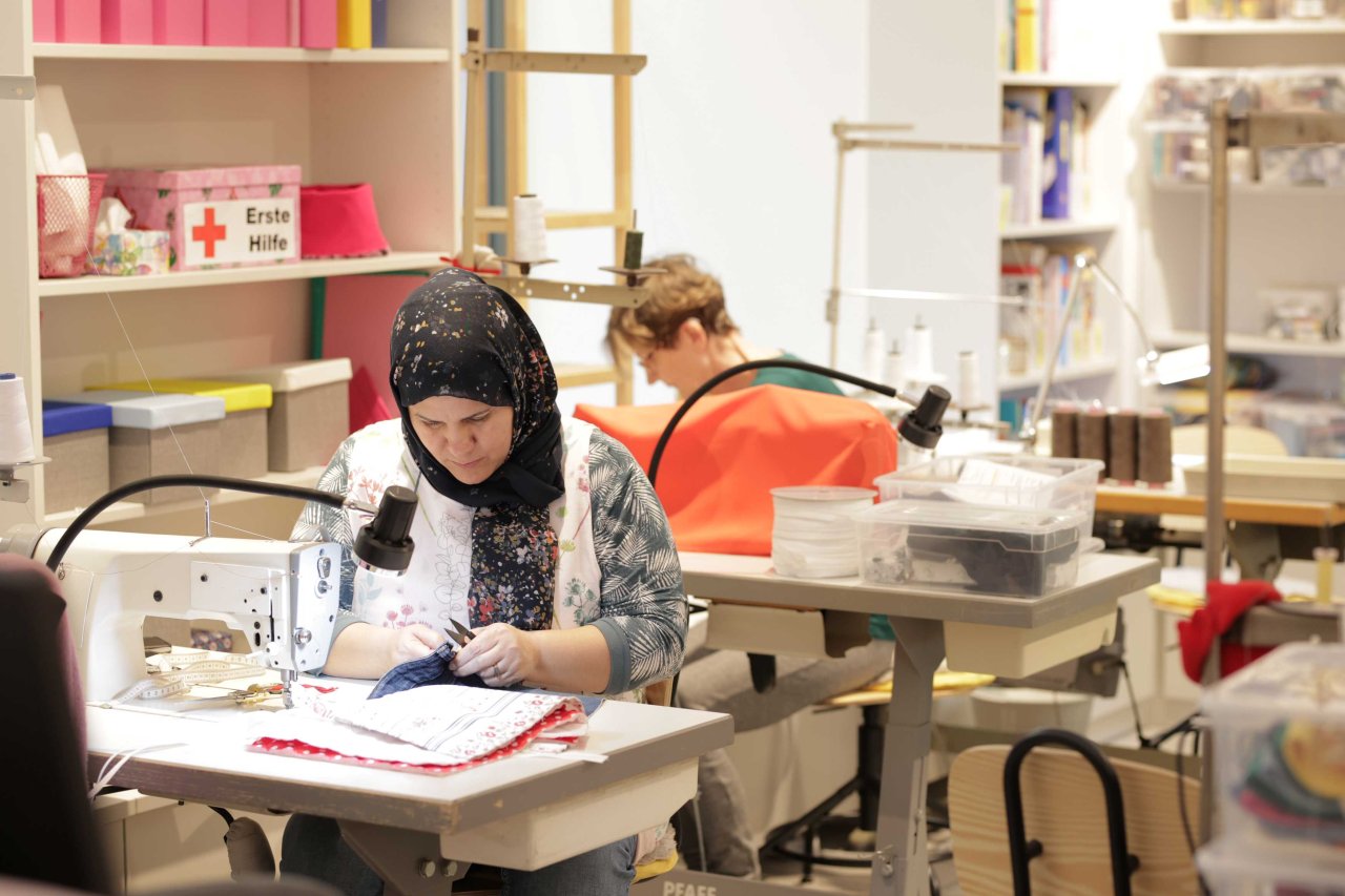 Zwei Frauen beim Nähen in einer Werkstatt.