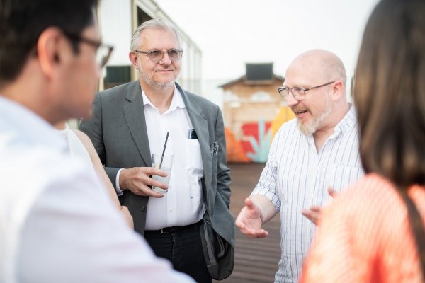 Gruppe von vier Personen im Gespräch auf der Terrasse. 