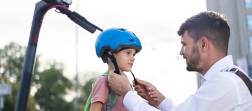 Ein Vater setzt seinem Sohn einen Helm auf.