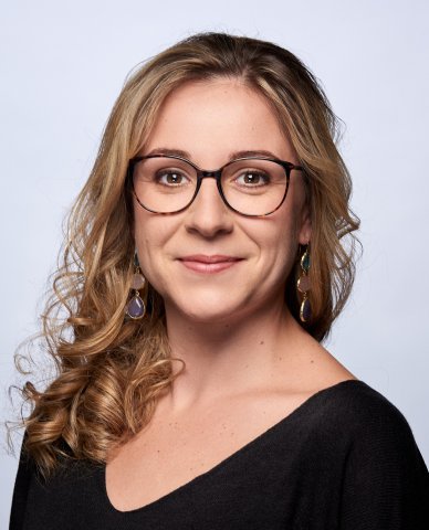 Frau mit Brille lächelt in die Kamera.