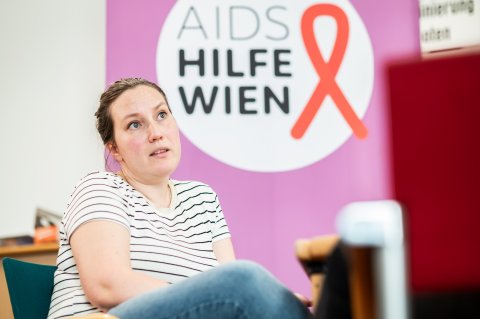 Frau im Gespräch vor Hintergrund der AIDS Hilfe Wien 