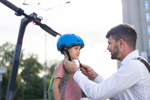 Ein Vater setzt seinem Sohn einen Helm auf.