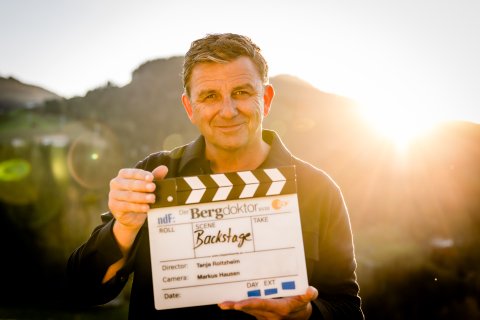Mann im Bergpanorama mit Filmklappe
