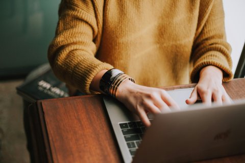 Frau sitzt an Laptop und arbeitet