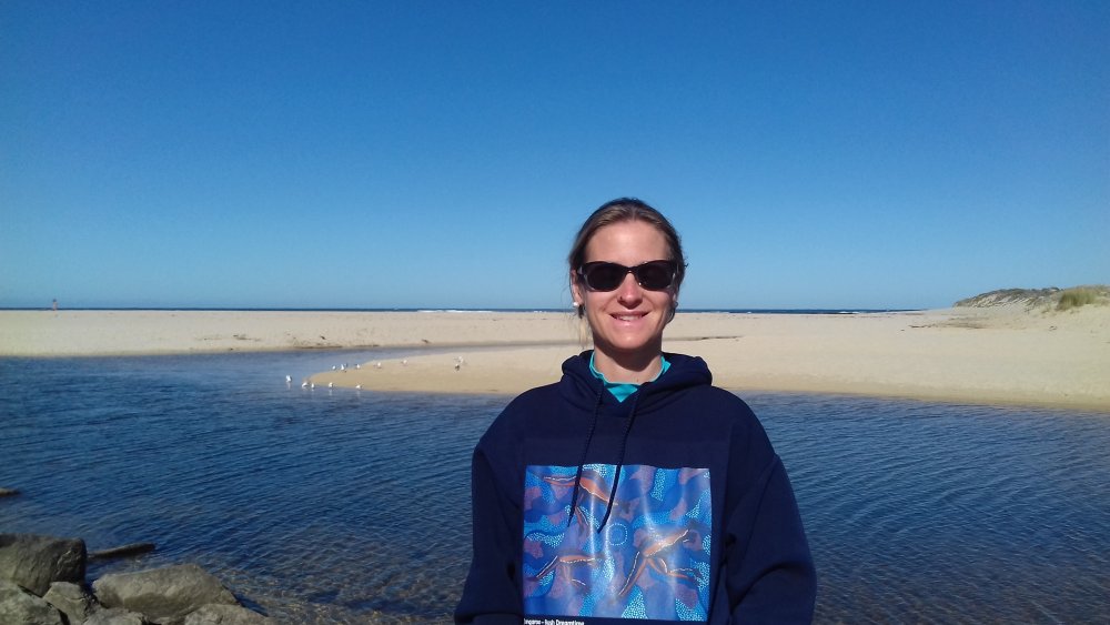 Frau mit Sonnenbrille steht an einem Fluss.