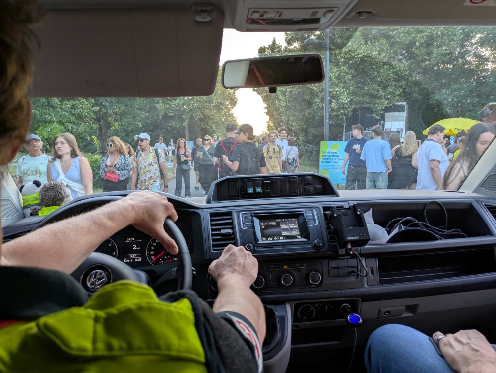 Aufnahme aus dem Auto heraus - man sieht aus der Windschutzscheibe hinaus auf eine Menge an Menschen, die vor und rund um das Einsatzfahrzeug stehen, wodurch das Fahrzeug nur im Schritttempo fahren kann.