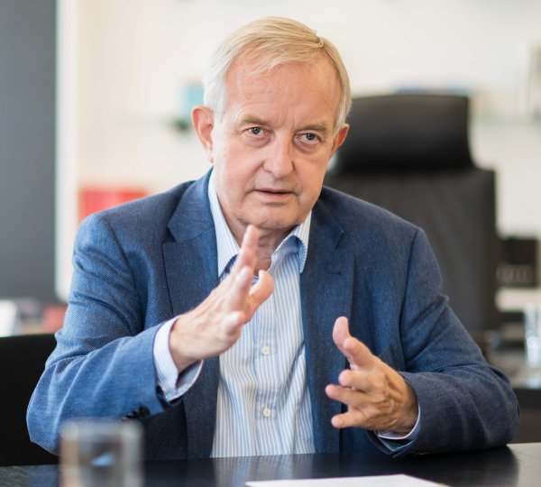 Mann mit Hemd und Sakko sitzt am Schreibtisch.