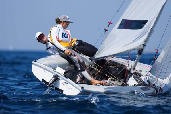 Zwei Personen, eine Frau und ein Mann, an Bord eines Segelboots, das sich im Wind stark neigt.