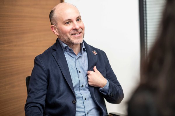 Der Arzt, Funktionär und Vorsitzender des Verwaltungsausschusses des Wohlfahrtsfonds Michael Lazansky sitzt bei einem Gespräch und lächelt, während er die linke Hand am Revers des Sakko hält. 