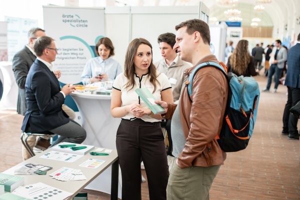 Frau berät Mann an einem Messestand