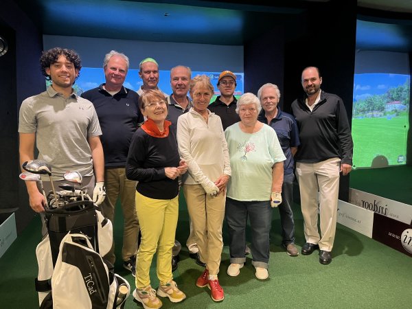 Sieben Männer und drei Frauen auf einem Indoorgolf-Feld.