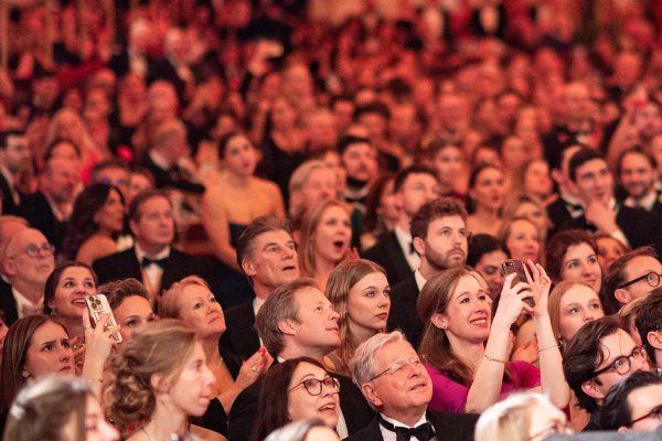 Zahlreiche Ballbesucherinnen und Besucher sehen gespannt nach oben.